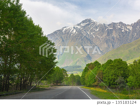 Road leading to snowy caucasus mountains in georgia 135183124