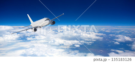 Commercial jet flying above fluffy white clouds 135183126