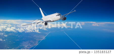 White passenger airplane flying high above clouds and ocean 135183127