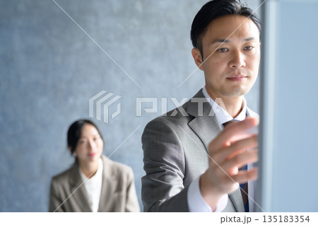 会議でホワイトボードに記入する男性 135183354