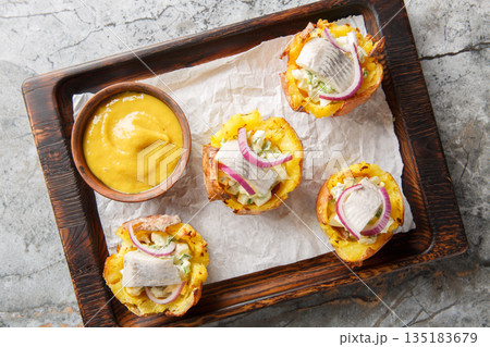 Crispy Loaded Potato Cups with egg salad and herring close-up on a wooden board. Horizontal top view Crispy Loaded Potato Cups with egg salad and herring close-up on a wooden board. Horizontal top view 135183679