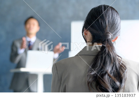 ホワイトボードの前でピンマイクを使ってプレゼンをする日本人男性 ホワイトボードの前でピンマイクを使ってプレゼンをする日本人男性 135183937