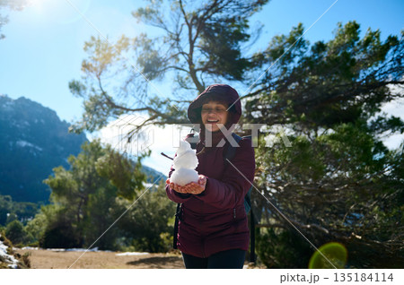 Cheerful Woman Outdoors Holding Snowman On Mountain Trail In Winter Sunshine 135184114