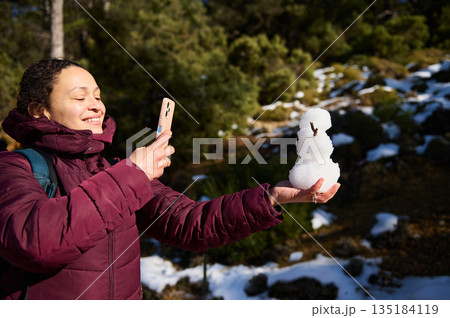 Woman in Purple Jacket Takes Selfie With Snowman Outdoors During Winter Adventure 135184119