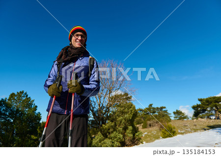 Smiling Man With Trekking Poles Outdoors In Bright Winter Sun Amid Blue Sky Smiling Man With Trekking Poles Outdoors In Bright Winter Sun Amid Blue Sky 135184153