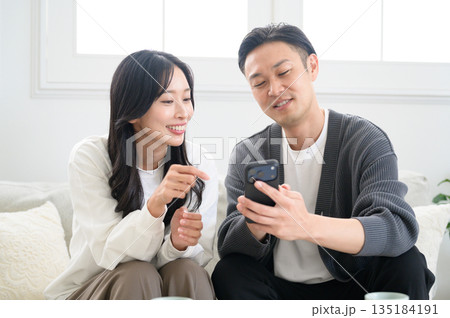 ソファに座ってスマホを見てリラックスする男女 135184191