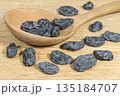 Dark raisins and wooden spoon on the wooden surface 135184707