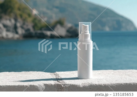 A white bottle with a cream dispenser stands on a white surface, with the sea and mountains in the background. Clean template for brand presentation. 135185653