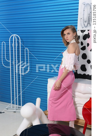 Caucasian stylist finetuning pink skirt against fashionable backdrop Caucasian stylist finetuning pink skirt against fashionable backdrop 135185706