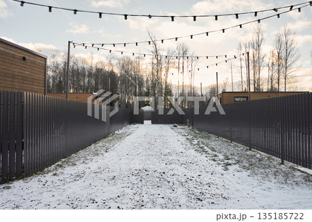 Bright winter passage bordered by fences with overhead illumination 135185722