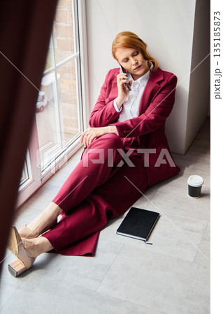 Individual dressed in winecolored suit engaging in conversation 135185873