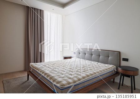 Tranquil bedroom with upholstered headboard and bare mattress Tranquil bedroom with upholstered headboard and bare mattress 135185951