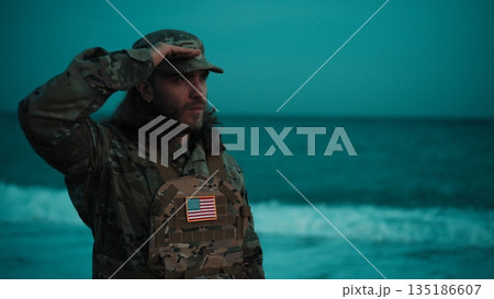 On a beach, an American soldier salutes near the ocean During Veterans Day On a beach, an American soldier salutes near the ocean During Veterans Day 135186607