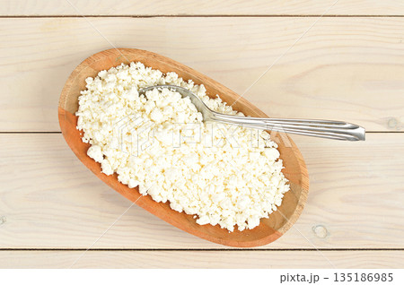crumbly cottage cheese in a wooden plate 135186985