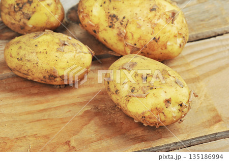 whole raw potatoes in their skins on a wooden whole raw potatoes in their skins on a wooden 135186994