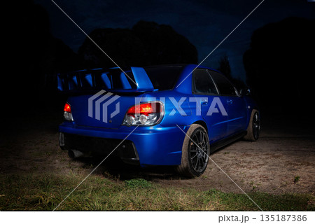 Sleek blue sports car in night backdoor behind. Sleek blue sports car in night backdoor behind. 135187386