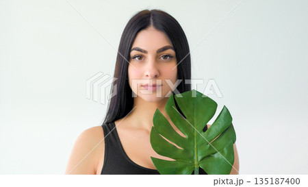 Tropical treatment. Eco cosmetic. Pretty woman showing exotic green leaf. Fresh natural power healthy skin care isolated on white. Tropical treatment. Eco cosmetic. Pretty woman showing exotic green leaf. Fresh natural power healthy skin care isolated on white. 135187400