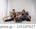asian personal trainers demonstrating partnerassisted stretch at home 135187627