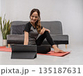 Female engaged in workout while watching tablet comfortably 135187631