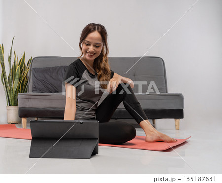 Female engaged in workout while watching tablet comfortably 135187631