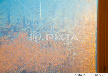 Golden sun shining through frozen window Golden sun shining through frozen window 135187726