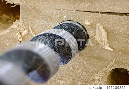 A drill makes a hole in a wooden board 135189283