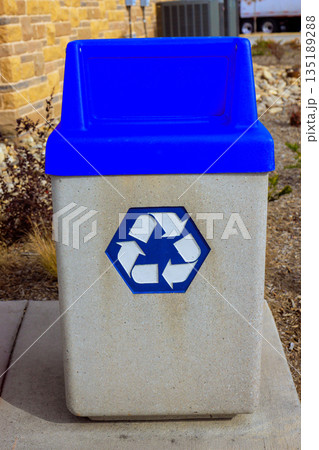 Blue recycling bin is placed in public space with concrete natural surroundings items can be discarded here. 135189288