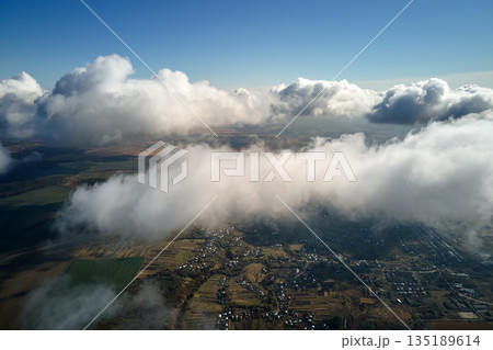 Aerial view from airplane window at high altitude of earth covered with white puffy cumulus clouds 135189614
