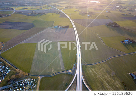 Aerial top view of rural landscape, modern highway road and small farm buildings on spring green field background. Drone photography. Aerial top view of rural landscape, modern highway road and small farm buildings on spring green field background. Drone photography. 135189620