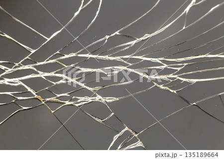 Abstract pattern dark gray background. Crackled screen of mobile cellphone. Gadget repair and maintenance concept. Abstract pattern dark gray background. Crackled screen of mobile cellphone. Gadget repair and maintenance concept. 135189664