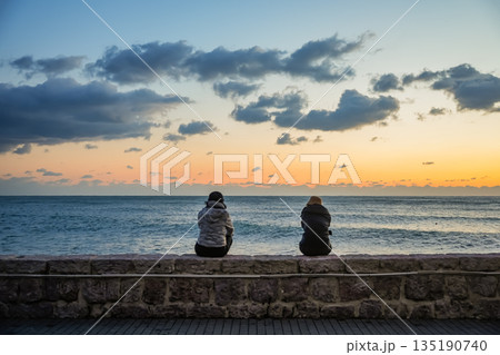 Two Silhouettes Sitting and Watching Sea Sunset 135190740