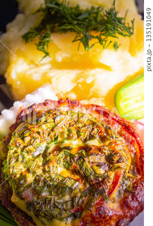 Baked meat with cheese and mashed potatoes with fresh vegetables as a side dish Baked meat with cheese and mashed potatoes with fresh vegetables as a side dish 135191049