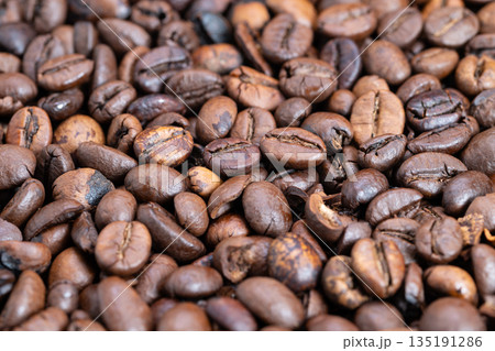 Detailed medium roast beans displaying glossy finish and warm hues, Macro image of varying roasted coffee beans showcasing rich brown shades and matte surface texture Detailed medium roast beans displaying glossy finish and warm hues, Macro image of varying roasted coffee beans showcasing rich brown shades and matte surface texture 135191286