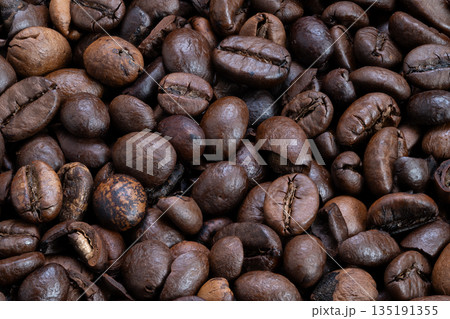 Macro study of roasted coffee beans highlighting cracked surfaces and grainy texture, highcontrast lighting emphasizes tactile detail for product photography and texture backdrops 135191355