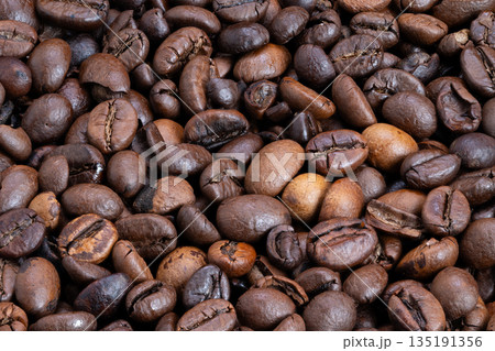 Shiny roasted coffee beans, Detailed shot of oily roasted coffee beans with rich aroma, Macro image of glazed roasted coffee beans highlighting their deep color and scent Shiny roasted coffee beans, Detailed shot of oily roasted coffee beans with rich aroma, Macro image of glazed roasted coffee beans highlighting their deep color and scent 135191356