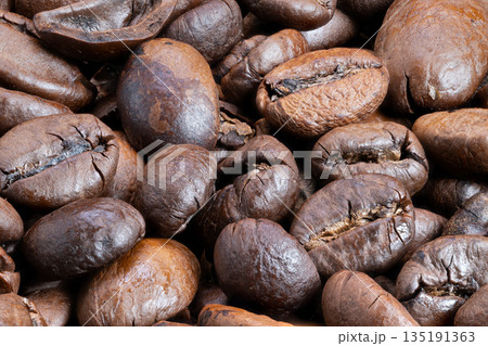 Coffee bean closeup, Intimate shot capturing oily sheen and cracks of freshly roasted beans, Closeup image emphasizing rich textures and warm ambiance of gourmet coffee beans Coffee bean closeup, Intimate shot capturing oily sheen and cracks of freshly roasted beans, Closeup image emphasizing rich textures and warm ambiance of gourmet coffee beans 135191363