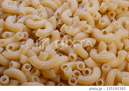 Uncooked spiral noodles with coarse semolina, Prepared elbowshaped pasta with visible semolina grains, Raw pasta arranged showcasing coarse semolina grains for cooking or display 135191385