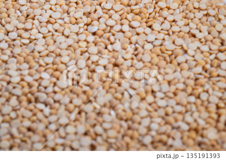 Pea grains closeup, Granular pea groats with warm natural light illumination, Close shot of beige pea groats highlighting coarse surface in warm natural kitchen setting Pea grains closeup, Granular pea groats with warm natural light illumination, Close shot of beige pea groats highlighting coarse surface in warm natural kitchen setting 135191393