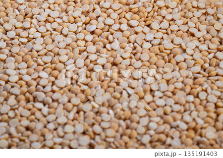 Closeup yellow split peas covering surface, dry groats with warm beige tones, shallow depth, natural light, repeating pattern for backgrounds and food packaging Closeup yellow split peas covering surface, dry groats with warm beige tones, shallow depth, natural light, repeating pattern for backgrounds and food packaging 135191403