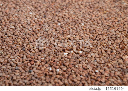 Close up buckwheat groats texture, earthy brown kernels scattered across flat surface, shallow depth of field, natural lighting, crisp detail for food packaging and social media Close up buckwheat groats texture, earthy brown kernels scattered across flat surface, shallow depth of field, natural lighting, crisp detail for food packaging and social media 135191494