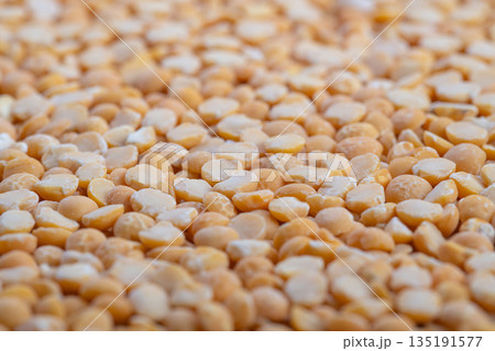 Warm natural light on legumes, Closeup of yellow split peas under warm natural illumination, Captivating image featuring dry halved legumes with cozy rustic food ambiance Warm natural light on legumes, Closeup of yellow split peas under warm natural illumination, Captivating image featuring dry halved legumes with cozy rustic food ambiance 135191577