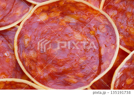 Spicy sausage slices with cheese, Closeup view of spicy sausage garnished with cheese, An upclose view of seasoned sausage slices complemented by cheese and drizzle of oil 135191738