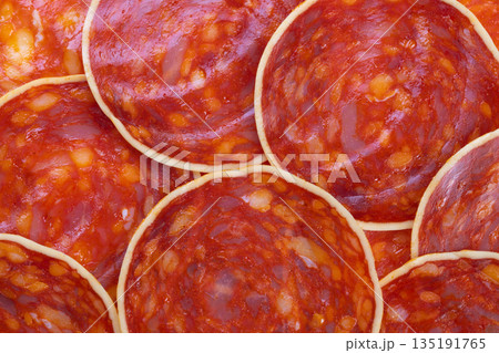 Tapas chorizo slices layered on rustic board, evoking social gathering vibe with savory aroma and glossy spice flecks perfect for party menu and social media food posts 135191765