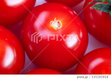 Close up glossy cherry tomato center, intense red sheen and mirrorlike skin, studiolit surface conveying premium culinary garnish, ideal for chef plating and gourmet food styling 135191918