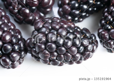 Wild blackberries closeup with rustic texture and natural imperfections, deep color gradient and organic shapes evoking foraging, outdoor seasonality and natureled food stories 135191964