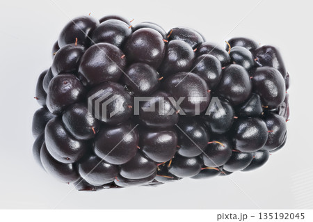Blackberry texture hues, Deep purple blackberry showcasing drupelet density, Closeup of ripe blackberry highlighting natural lighting and textured clusters of drupelets 135192045