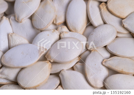 Seed shell imagery, Pumpkin seed shells with warm matte surfaces, Overlapping pumpkin seed shells display subdued shadows and warm earthy tones in rustic environment 135192160