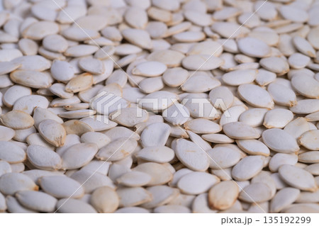 Pumpkin seed closeup, Raw seed layer visualization detailed, Unprocessed pumpkin seeds filling frame, Textured raw pumpkin seeds with soft lighting and neutral background 135192299