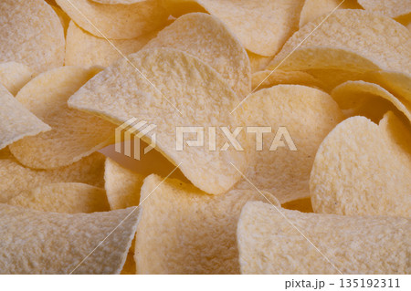 Golden salted potato chip closeup, Appetizing crispy potato slices with salt crystals, Highly detailed image of crispy potato chips with salt and inviting warm ambiance 135192311