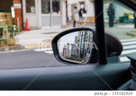 都会の渋滞と街並みを映し出す走行中の車のサイドミラー 135192924